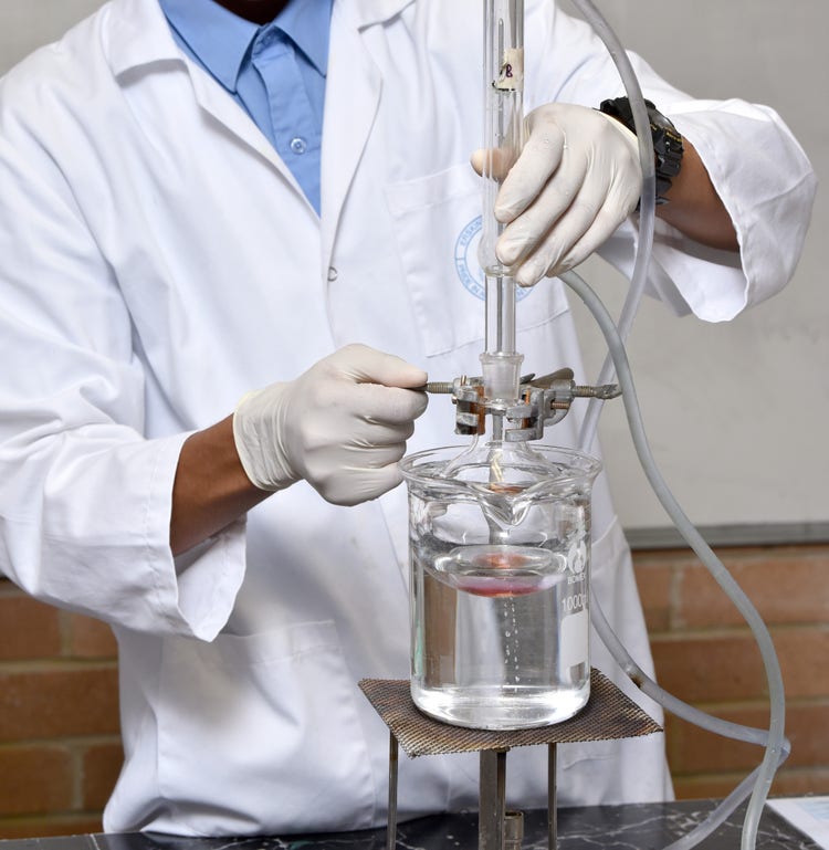 A student working on a science experiment using a Bunsen Burner and other science equipment.
