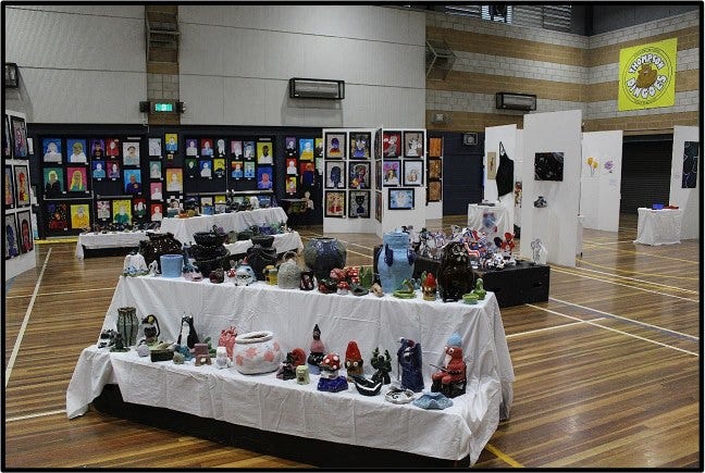 A picture showcasing the artwork of many students in the School hall for arts in the park.