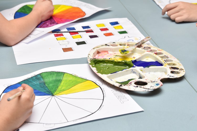 Students painting a colour wheel with a paint palette sitting on the table.