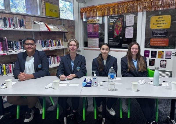 4 Students sitting at a table participating in Debating