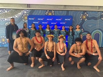 A group of 8 female students and 6 male students in front of a PCYC sign dressed in traditional Pacific Island Attire.