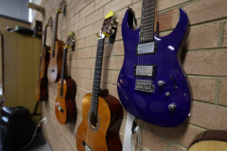 6 Guitars hanging on a wall.